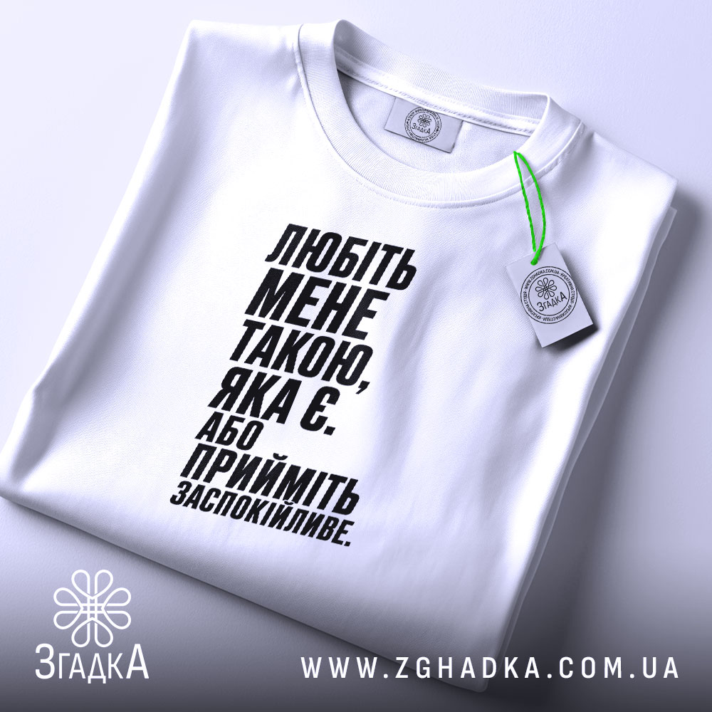 Футболка любіть мене такою яка є, біла, на столі, з етикеткою, бренд.