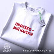 Футболка просеко на столі, біла, з червоним принтом, етикетка, бренд Згадка.