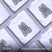 Футболка з принтом не буди звіра, на столі, біла, з кількома футболками,.