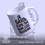 Чашка саме той ким себе вважаю, біла з кольоровим написом, вид знизу,.
