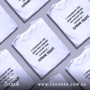 Футболка: біла, на столі, принт чорний, кілька футболок в кадрі.