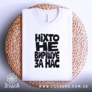 Складена футболка з чорним написом на плетеній поверхні.
