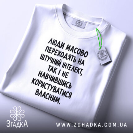 Футболка: складена, біла, з етикеткою, принт чорний.