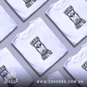 Кілька складених білих футболок із принтом «Пам’ятай поки є час», вигляд зверху.