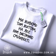 Футболка: складена, біла, з етикеткою.